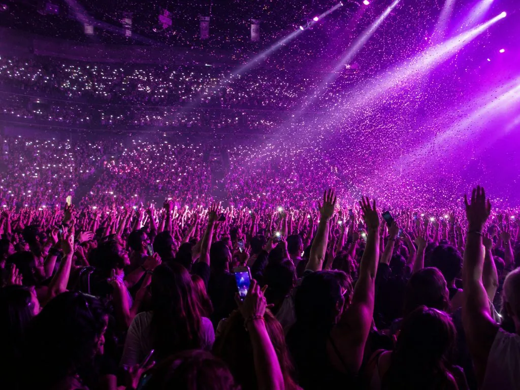 Crowd with phone lights up during an Unraveled Tour-style arena show